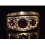 A 9ct gold ring set with three round cut garnets in star settings, 4.2g, size U