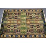 A large rug with geometric designs on a green ground with attached John Lewis label 'Marco Polo',
