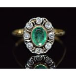 An 18ct gold ring set with an oval cut emerald surrounded by diamonds in a pierced setting, 3.3g,