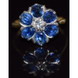 An 18ct gold ring set with a diamond surrounded by oval cut sapphires, each approximately 0.3cts,