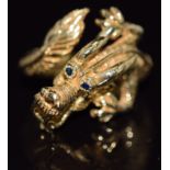 An 18ct gold ring in the form of a dragon with sapphire eyes, 10.7g, size O/P