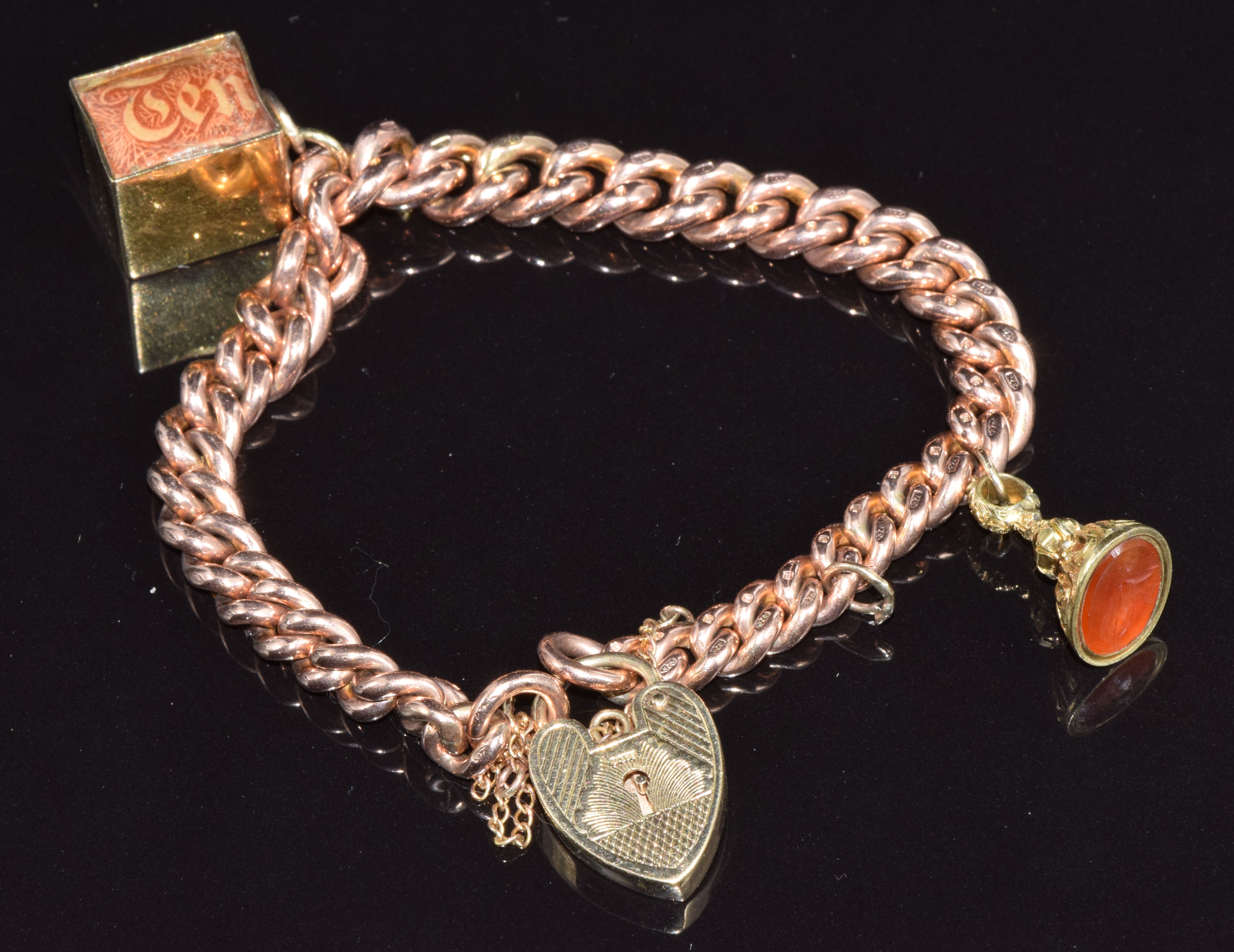 A 9ct rose gold bracelet with a 9ct gold ten shilling note charm and a Victorian fob set with agate,