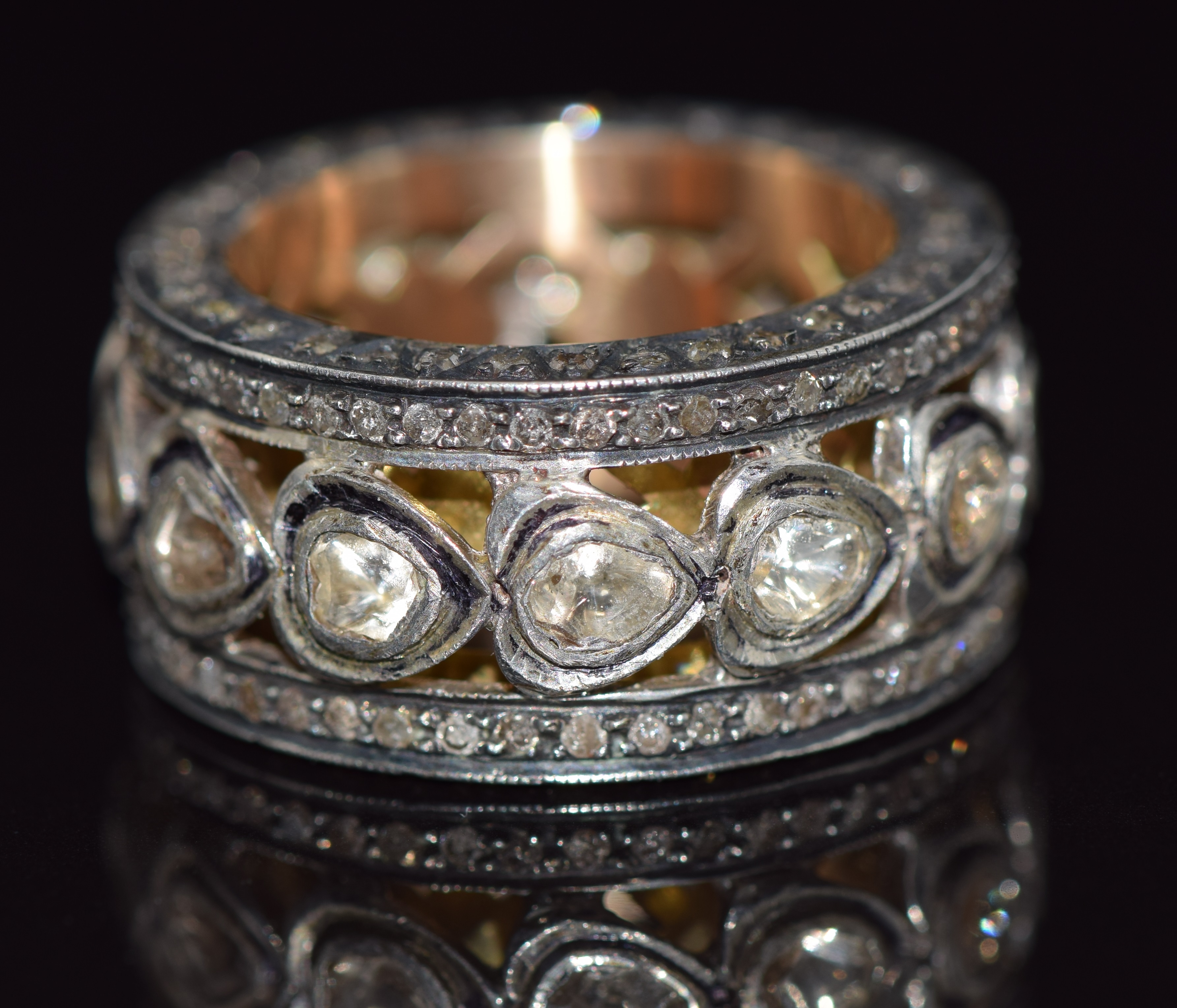 A large pierced gold ring set with diamonds in foiled settings with further diamonds to the edges
