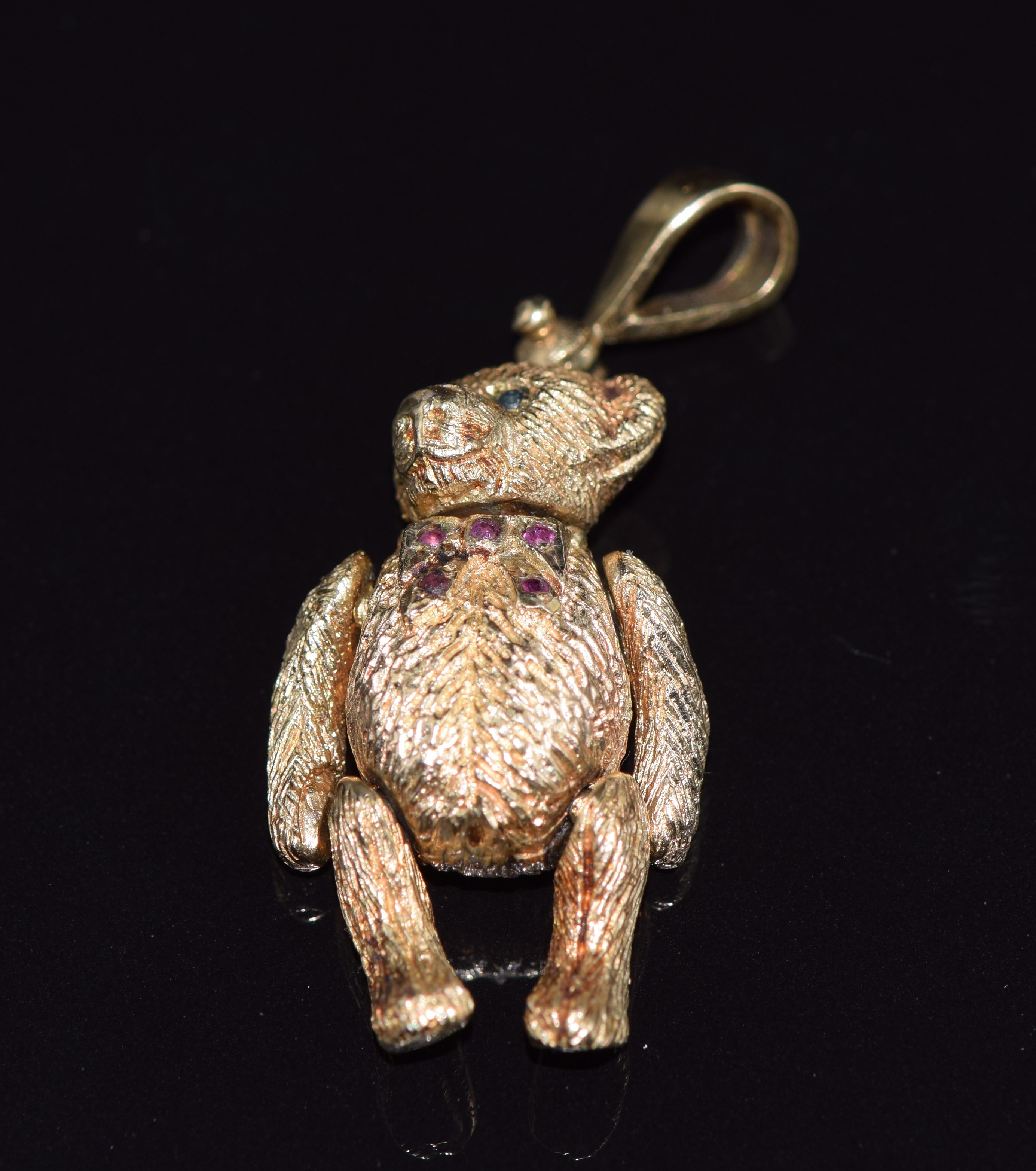 A 9ct gold articulated teddy bear pendant set with sapphires and rubies, 17.7g