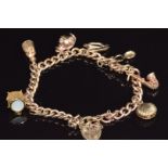 A 9ct gold charm bracelet with six 9ct gold charms including shell, drum, harp, etc, 28.3g