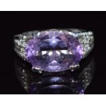 A 9k white gold ring set with an oval cut amethyst and diamonds to the shoulders and mount, 5.9g,