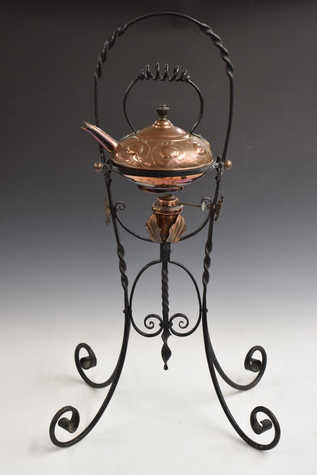 In the manner of W.A.S. Benson Arts and Crafts copper spirit kettle on wrought iron stand, H73cm