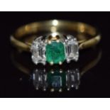 An 18ct gold ring set with an emerald cut emerald and two emerald cut diamonds, approximate