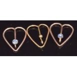 A 9ct gold heart shaped clip (0.5g) and two yellow metal tie/ collar clips set with a Montana