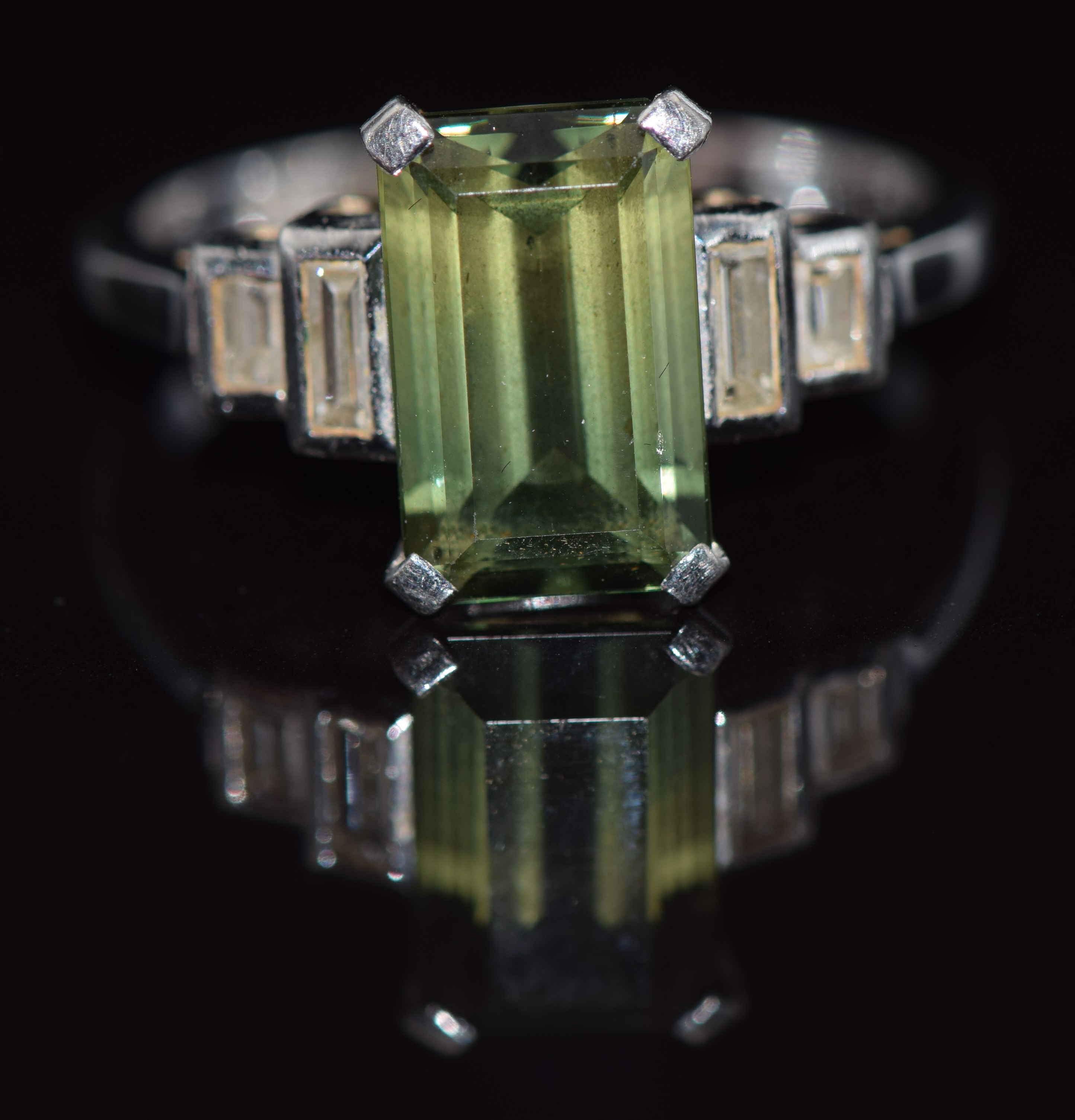 An 18ct white gold ring set with an emerald cut tourmaline and two baguette cut diamonds to each