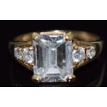 A 9ct gold ring set with an emerald cut cubic zirconia and further round cut cubic zirconia to the