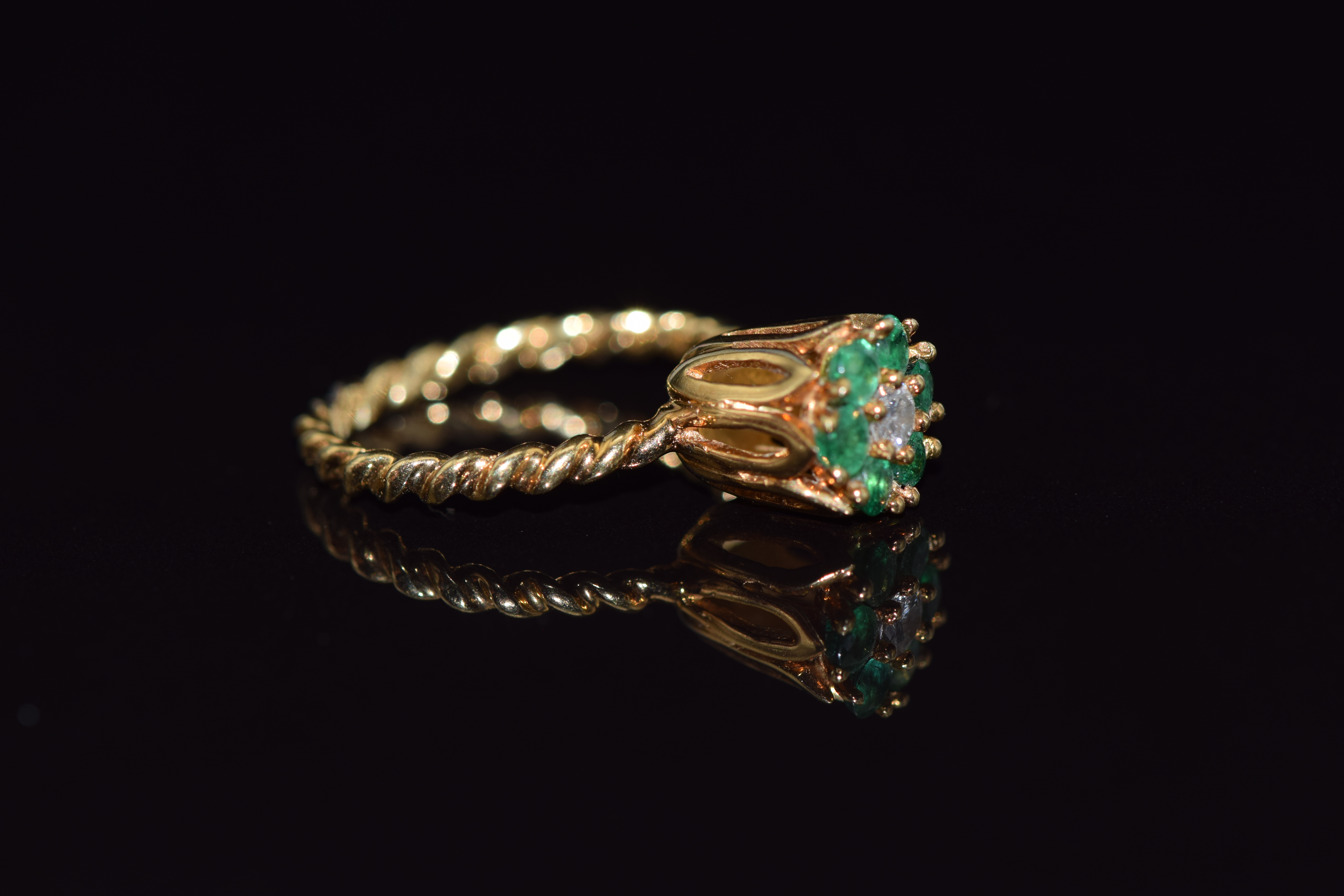 An 18ct gold ring set with a round cut diamond surrounded by emeralds on a rope twist band, 3.6g, - Image 2 of 2
