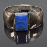 A silver bangle set with a rectangular lapis lazuli cabochon, 54.8g (5.4 x 6.2cm)