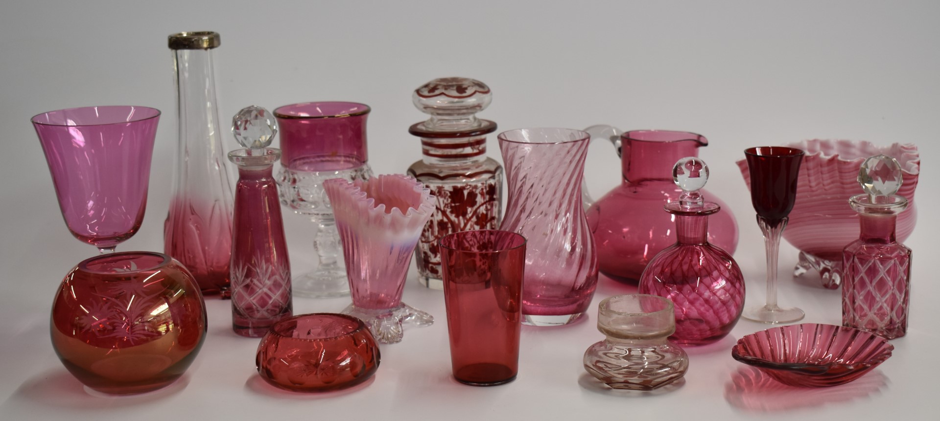 A collection of cranberry glass including enamelled, cut glass, and silver mounted examples, largest