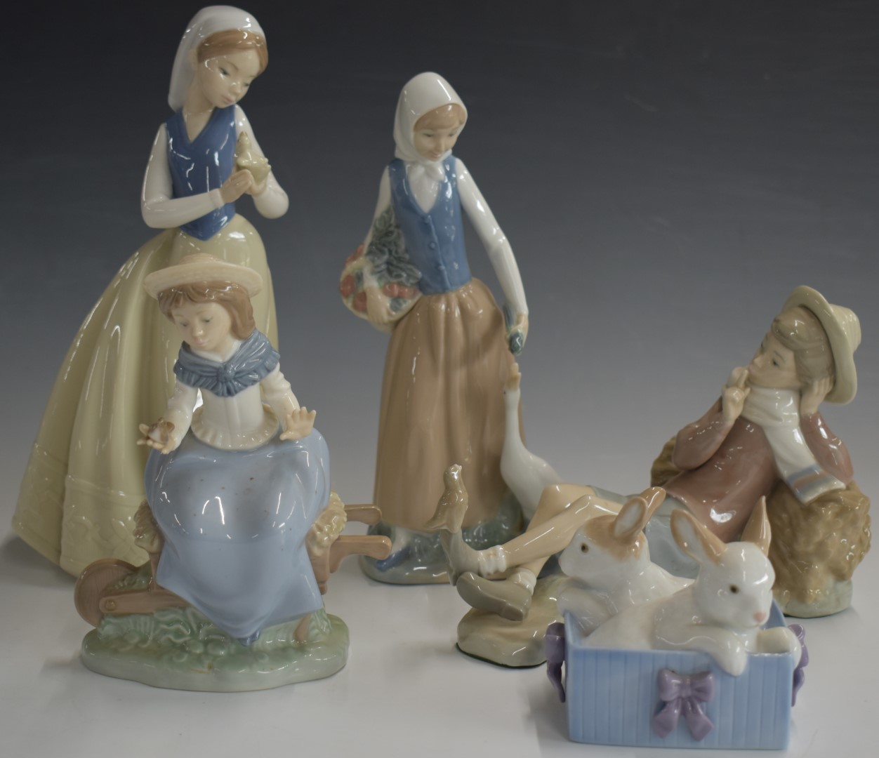 Lladro figure of a reclining boy and four Nao figures, tallest 27cm
