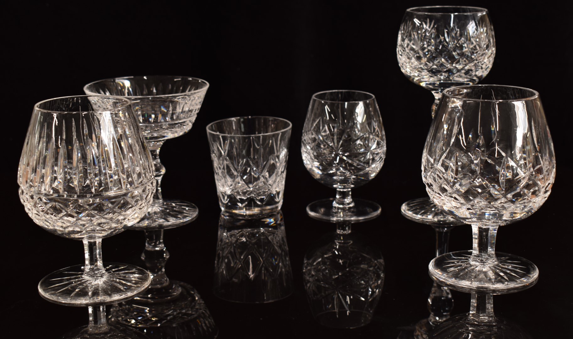 A collection of clear cut crystal drinking glasses including six Waterford brandy glasses, a set