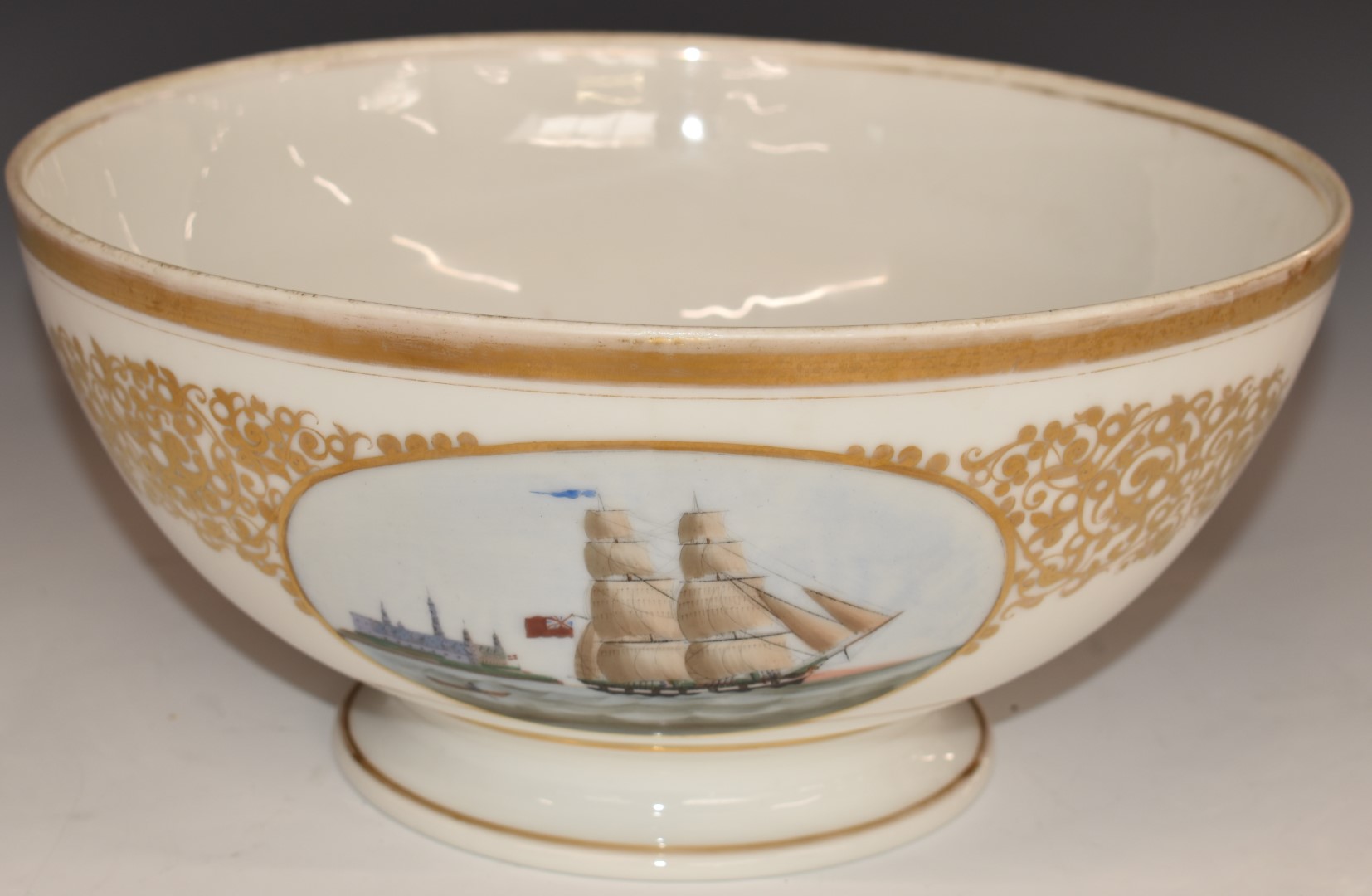A 19thC continental porcelain pedestal bowl with hand decorated cartouche of a British sailing