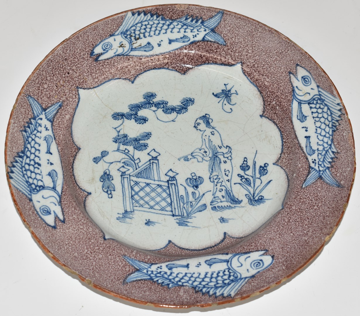 English Delft plate, London c1750, decorated with a chinoiserie garden scene within a border of four