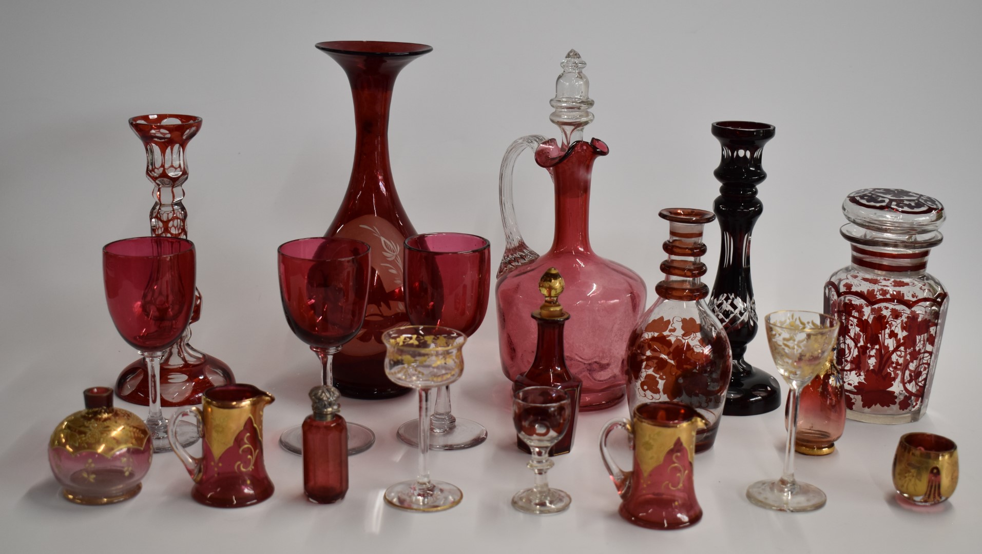 A collection of cranberry overlaid and cut glass items including a hallmarked silver mounted scent