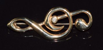 A 9ct gold brooch in the form of a musical note set with a diamond, 3g