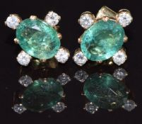 A pair of 9ct gold earrings set with oval cut emeralds, each approximately 1ct, and four diamonds,