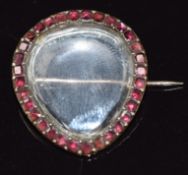 A late Georgian/ early Victorian brooch with glass locket centre within a border of garnets, 4.3g