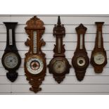 Five circa Edwardian aneroid wall barometers in carved wooden cases, to include one with silvered