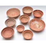 Nine Roman redware pottery bowls/dishes including two near pairs, some with incised or relief