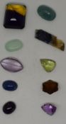 A collection of loose gemstones including grandite, amethyst, tourmaline, ametrine, quartz and