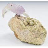 A quartz toucan with clear bill and pink body, with cabochon red stone eyes and silver claws