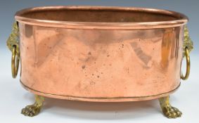 Copper planter with brass lion mask and ring handles, raised on four brass lion paw feet, length
