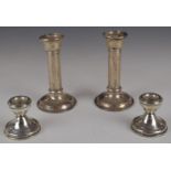 Two pairs of hallmarked silver candlesticks, larger pair Birmingham 1906, maker's mark rubbed,