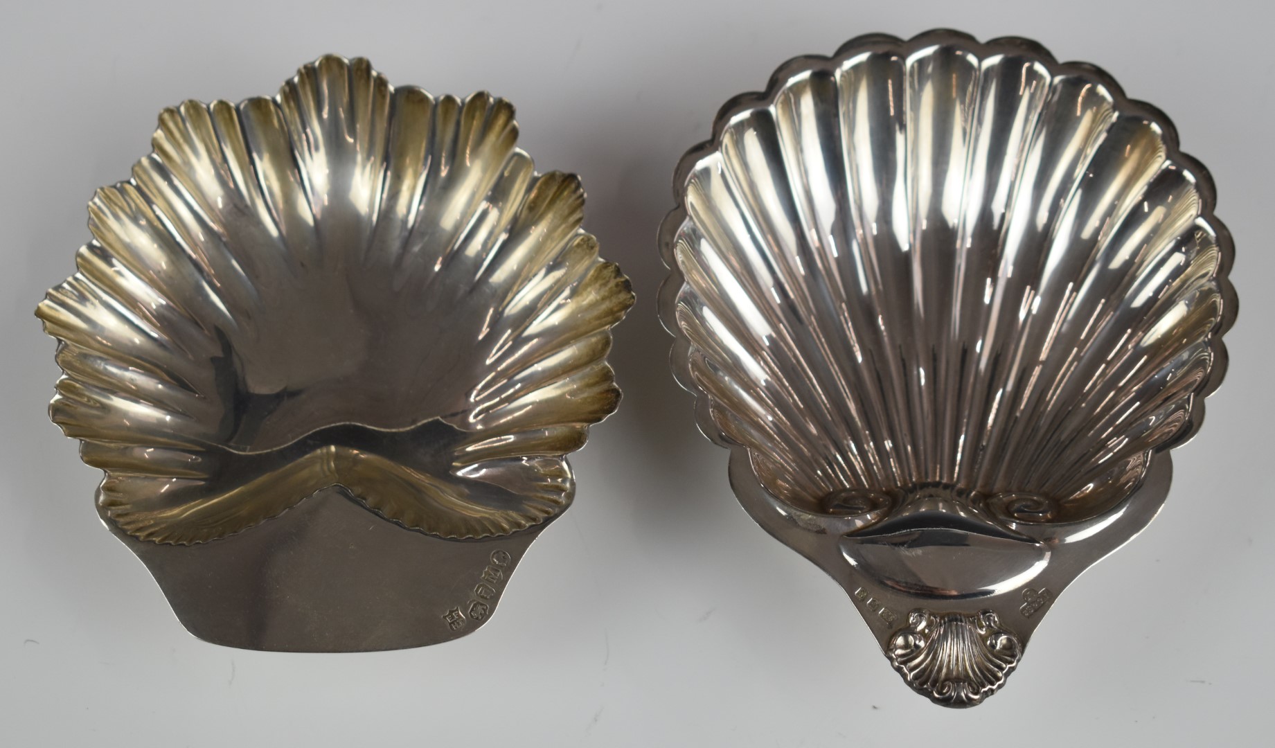 Two hallmarked silver shell shaped dishes, both raised on three ball feet, one Victorian, London