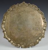 George V hallmarked silver salver with shaped edge, raised on three feet, inscribed to centre to