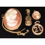 A 9ct gold brooch / pendant set with a cameo and three 9ct gold charms, 2g