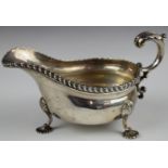 Edward VII hallmarked silver sauce boat with gadrooned edge and raised on three pad feet,