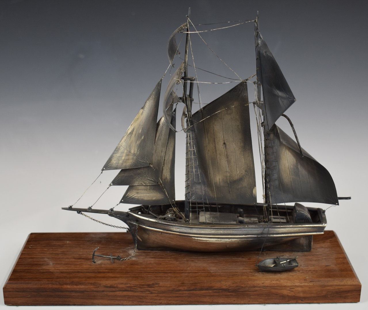 Hallmarked silver model of a sailing boat and tender, London 1980, maker Ammonite Ltd, on wooden