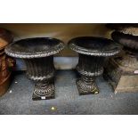 A pair of old black painted cast iron pedestal urns, 45.5cm high.