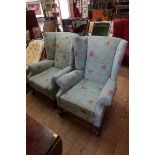 An old pair of walnut and upholstered wing armchairs, on cabriole legs with ball and claw feet to