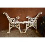 A pair of white painted cast iron bench ends, 73cm high x 60cm wide.
