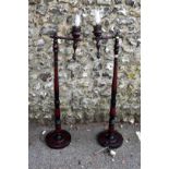 A pair of red stained wood standard lamps.