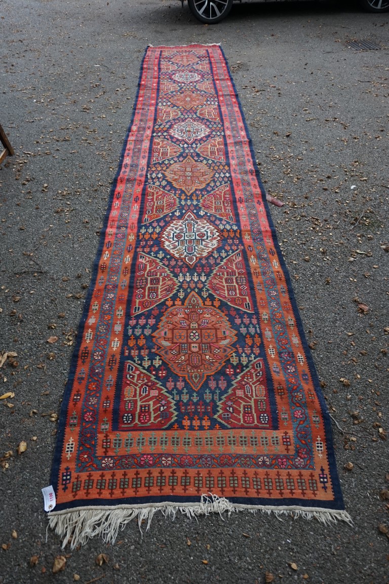 A long Tribal runner, having seven central medallions, with floral borders on a red and blue ground,