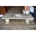A reconstituted stone garden bench, having a pair of pedestal supports, 141cm wide.