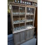(LC) A 19th century pine bookcase, with a pair of glazed panel doors above a large slide and