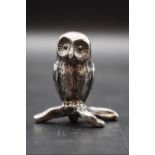 A white metal owl, 4.5cm high.