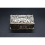 A white metal rectangular trinket box, having chased scroll and floral decoration, 10.7cm long.