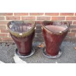 A large pair of glazed pottery twin handled garden pots on associated stands, the pots 50cm high.