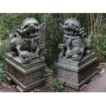 A pair of carved granite shi shi dogs on pedestals