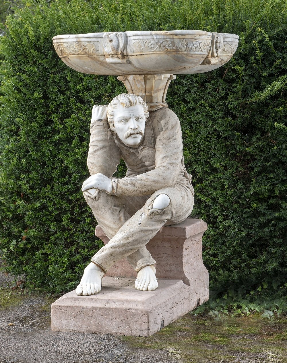 A carved marble and stone figure of a man supporting a bowl