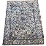 A PERSIAN WOOLLEN RUG OF TRADITIONAL DESIGN The central floral field contained within running